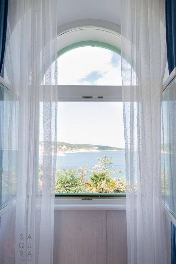 Großes Bogenfenster mit Vorhängen bietet einen weiten Blick auf das Meer und die Landschaft.