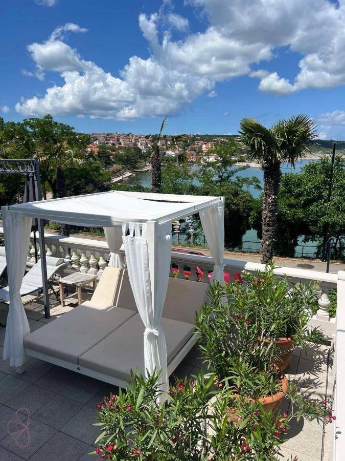 Sonniger Terrassenbereich mit luxuriösem Tagesbett und weitem Blick auf das Meer und die Stadt.