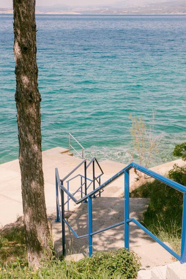 Treppe mit blauem Geländer führt direkt zum klaren, türkisfarbenen Meer.