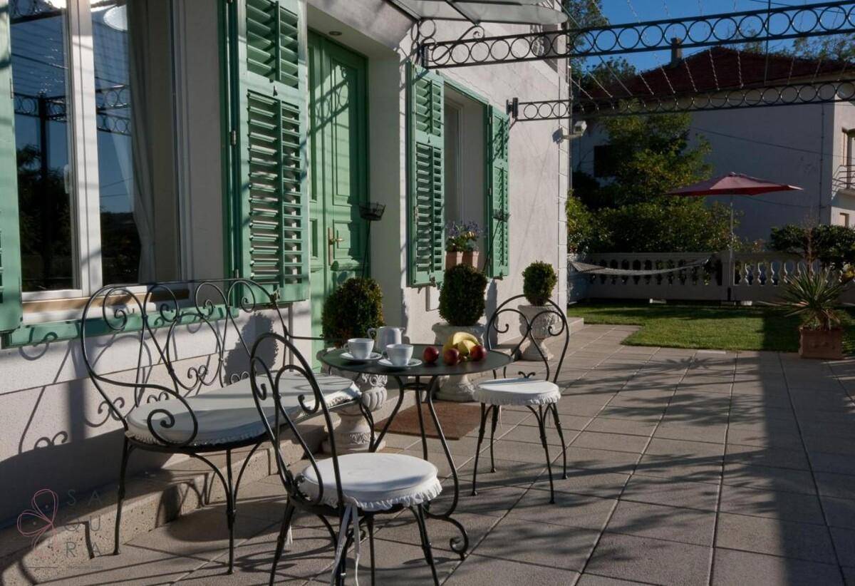 Gemütliche Terrasse mit schmiedeeisernen Möbeln und Blick auf den Gartenbereich.