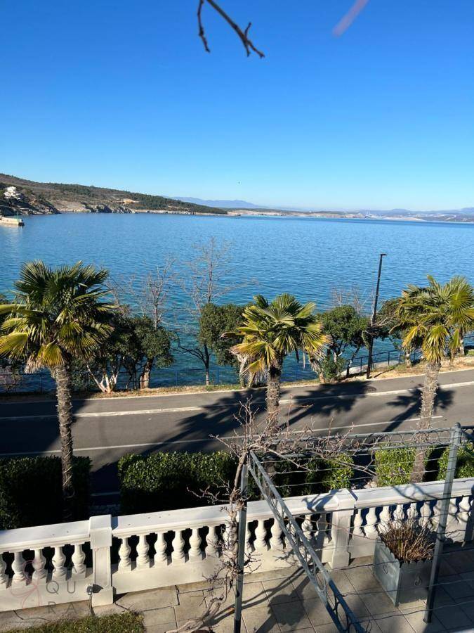 Panoramablick vom Balkon auf das glitzernde Meer und die Küstenlandschaft mit Palmen.