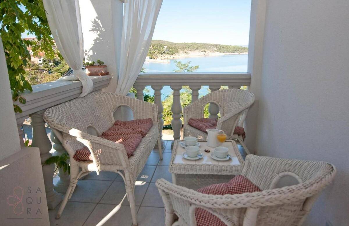 Kleiner Balkon mit Korbsesseln, Tisch und malerischem Blick auf das Meer.