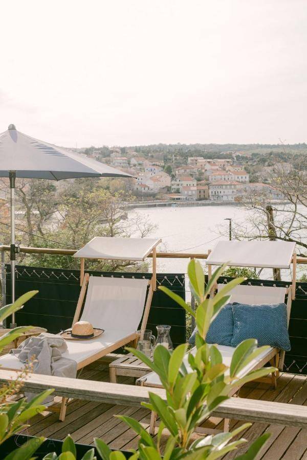 Entspannende Terrasse mit Liegestühlen, Sonnenschirm und Blick auf die Küstenstadt.