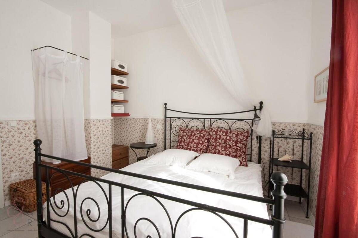 Gemütliches Schlafzimmer mit schmiedeeisernem Bett, floraler Tapete und roten Vorhängen.