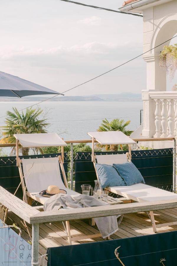 Sonniger Terrassenbereich mit Liegestühlen und weitem Blick auf das Meer und die Küste.