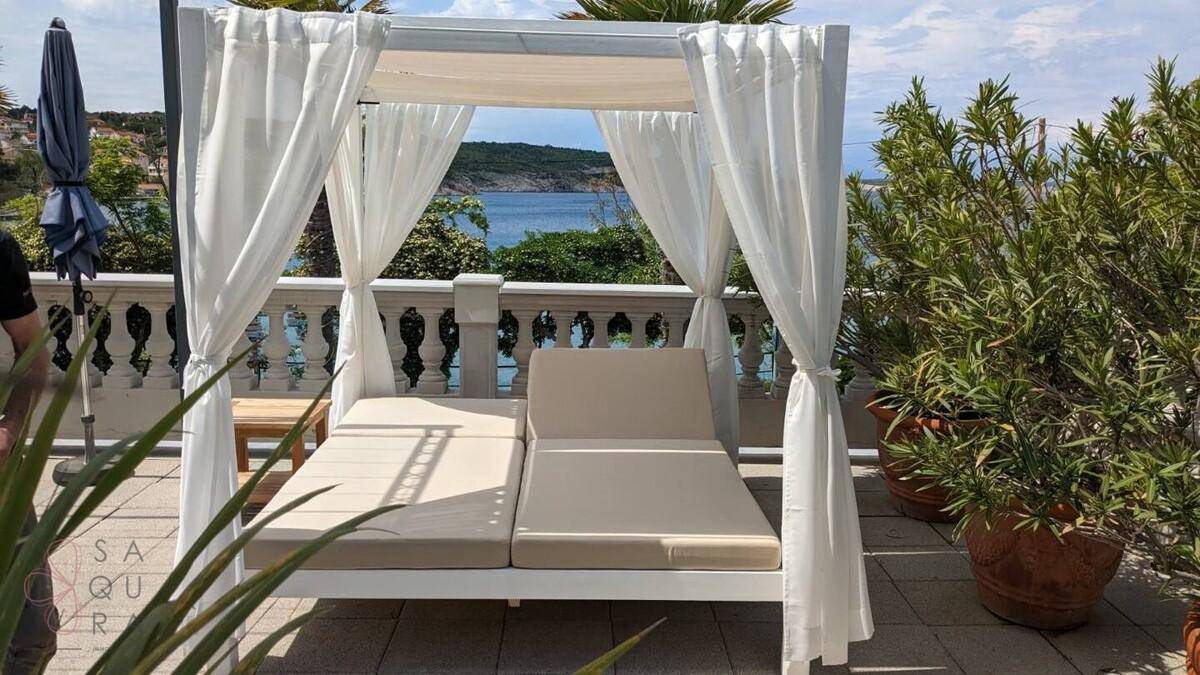 Geräumige Terrasse mit luxuriösem Tagesbett, Pflanzen und weitem Meerblick.