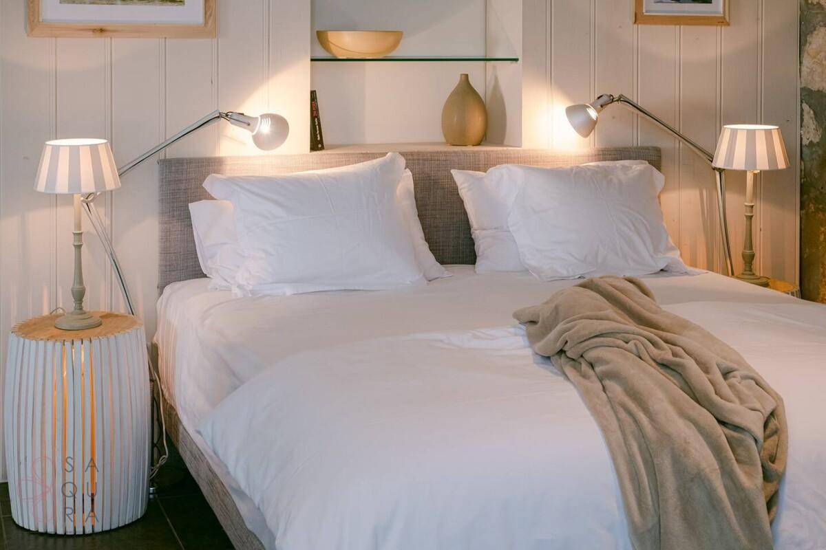 Modernes Schlafzimmer mit beigem Bett, Nachttischen und Leselampen.