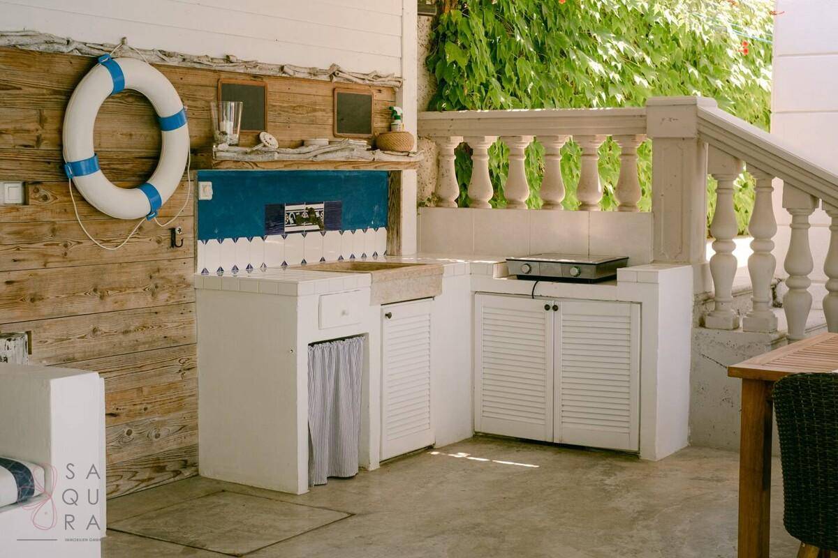 Funktionale Außenküche mit Spüle, Kochfeld und Stauraum auf einer gepflasterten Terrasse.