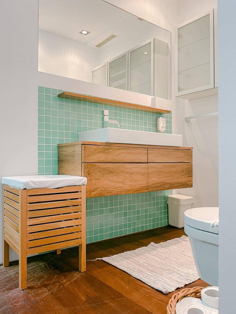 Modernes Badezimmer mit Holzwaschtisch, Aufsatzwaschbecken und mintgrünen Fliesen.