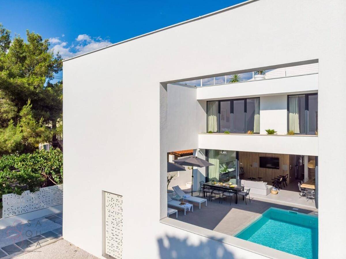Moderne Architektur der Villa mit großen Fensterfronten und integriertem Poolbereich.