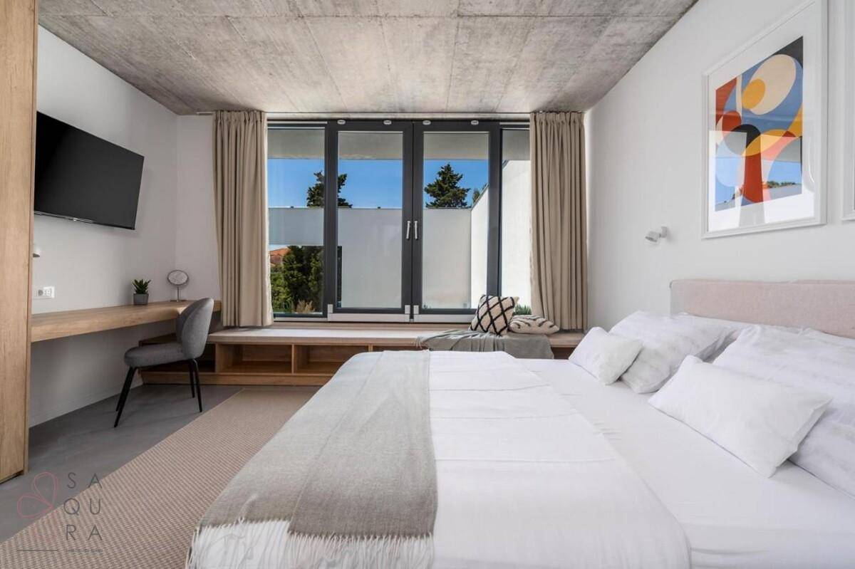 Helles Schlafzimmer mit großem Fenster, Sitzbank und Blick ins Grüne.