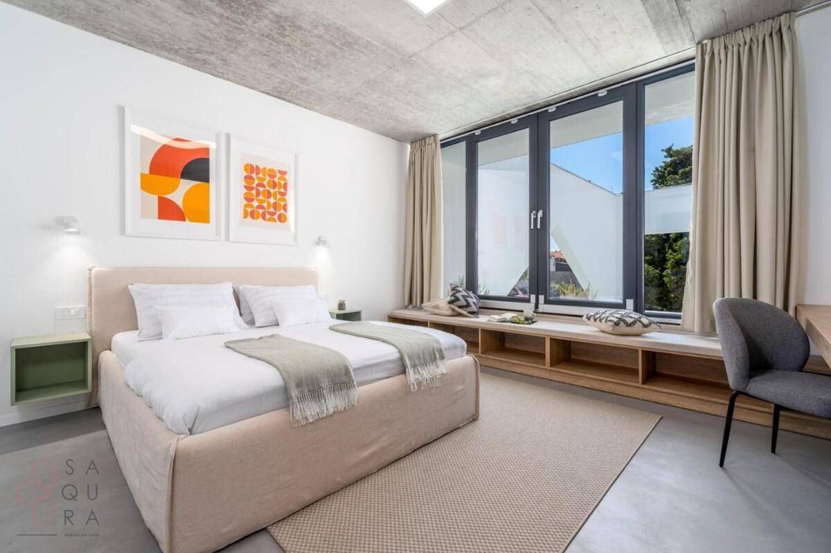 Helles Schlafzimmer mit Doppelbett, großem Fenster und integrierter Sitzbank.
