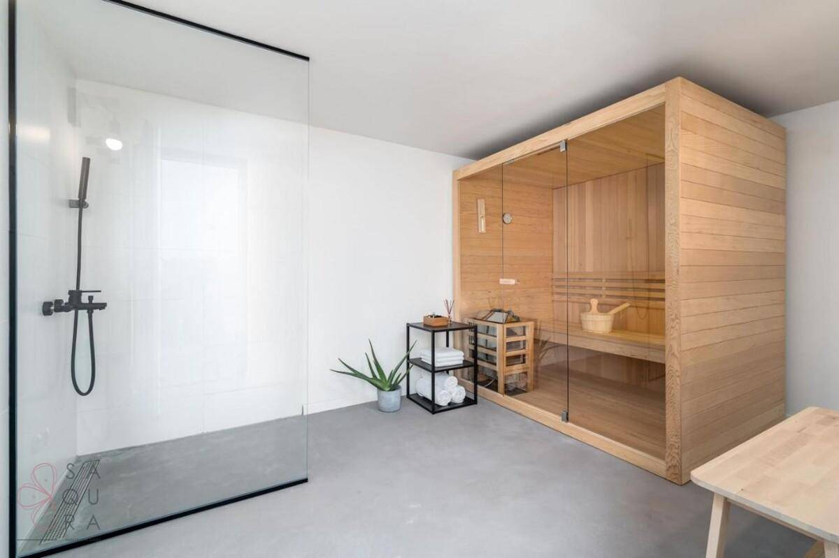 Moderner Wellnessbereich mit Sauna und begehbarer Dusche in minimalistischem Design.