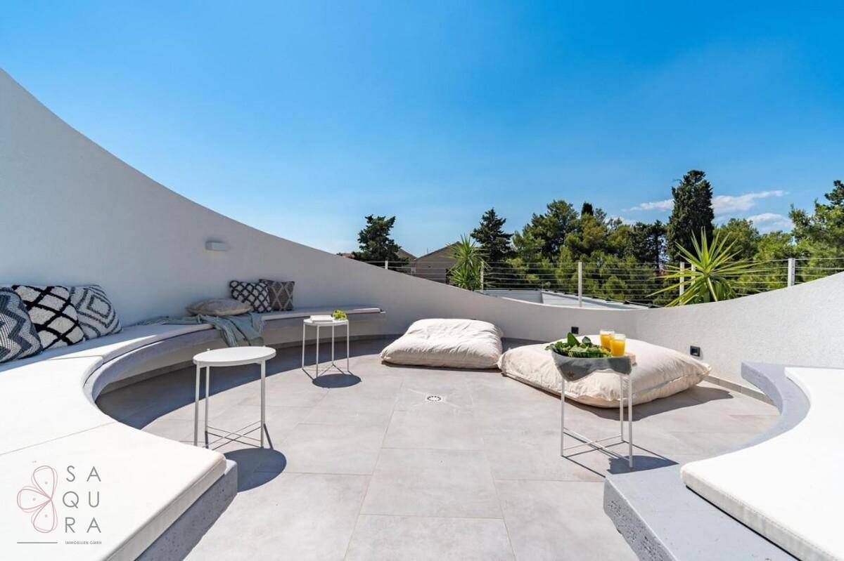 Runde Dachterrasse mit bequemen Sitzgelegenheiten und weitem Blick unter blauem Himmel.