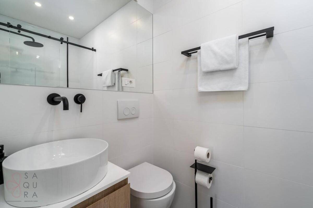 Modernes Badezimmer mit Waschtisch, Wand-WC und minimalistischen Armaturen.