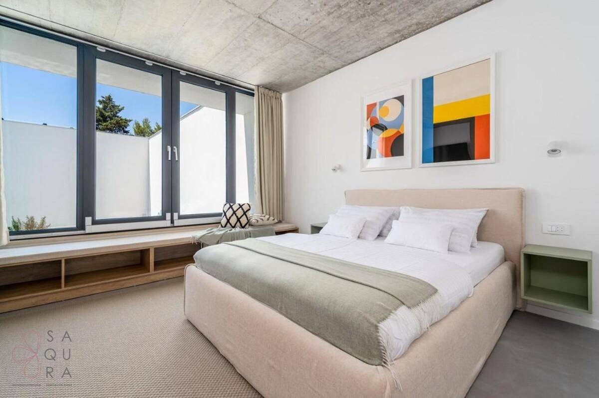 Modernes Schlafzimmer mit Doppelbett, großem Fenster und minimalistischer Einrichtung.