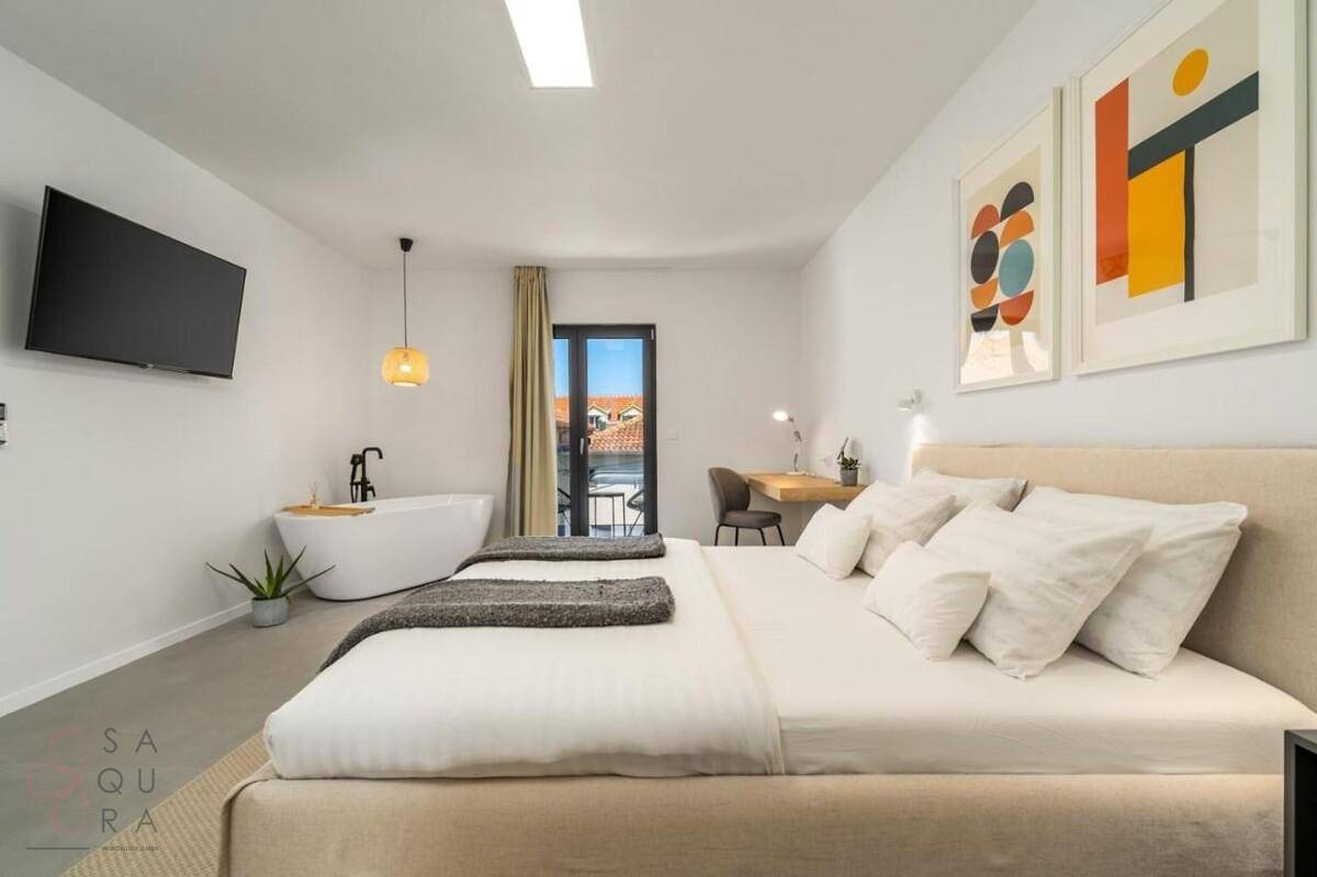 Helles Schlafzimmer mit Doppelbett, freistehender Badewanne und Balkonzugang.