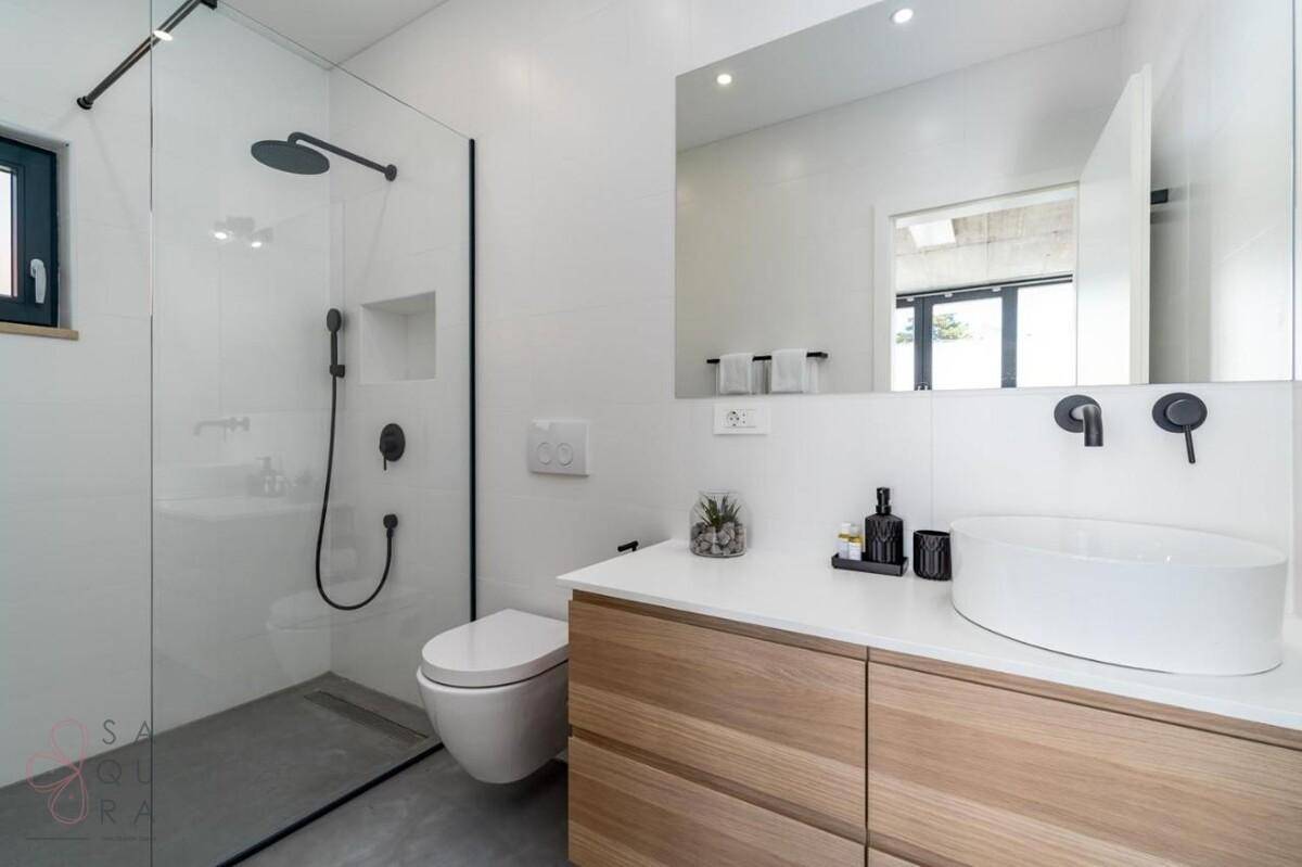 Modernes Badezimmer mit begehbarer Dusche, Waschtisch und Wand-WC in Weiß.