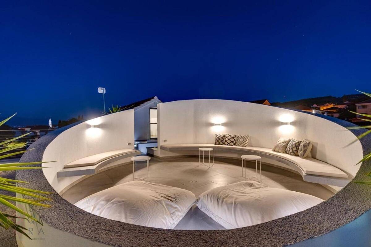 Runde Dachterrasse mit bequemen Sitzgelegenheiten und stimmungsvoller Beleuchtung bei Nacht.