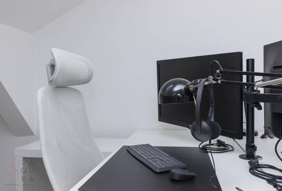 Moderner Arbeitsplatz mit zwei Monitoren und ergonomischem Stuhl in hellem Raum.