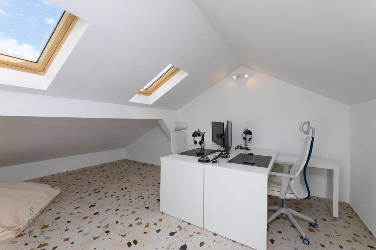 Helles Dachgeschoss-Büro mit Schreibtischen, Dachfenstern und Terrazzoboden.