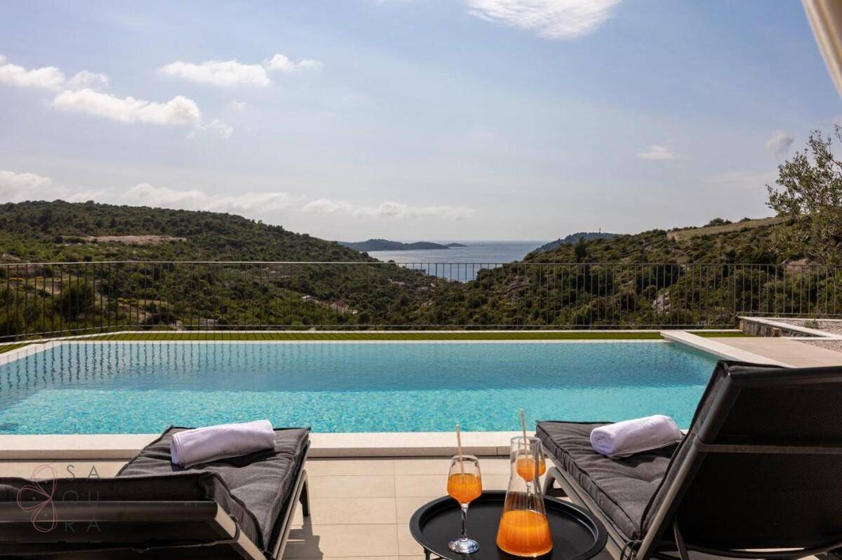 Erfrischender Pool mit Liegestühlen und atemberaubendem Meerblick, ideal für sonnige Tage.