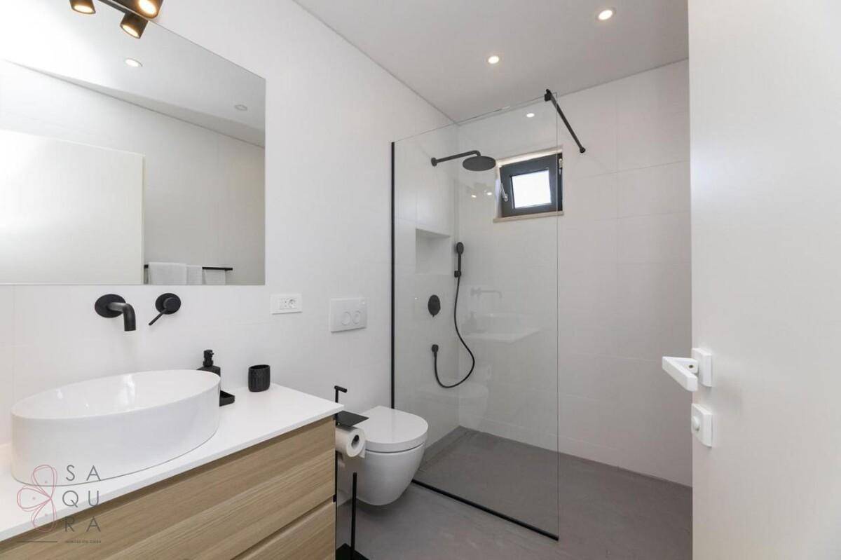 Modernes Badezimmer mit begehbarer Dusche, Waschtisch und Wand-WC.