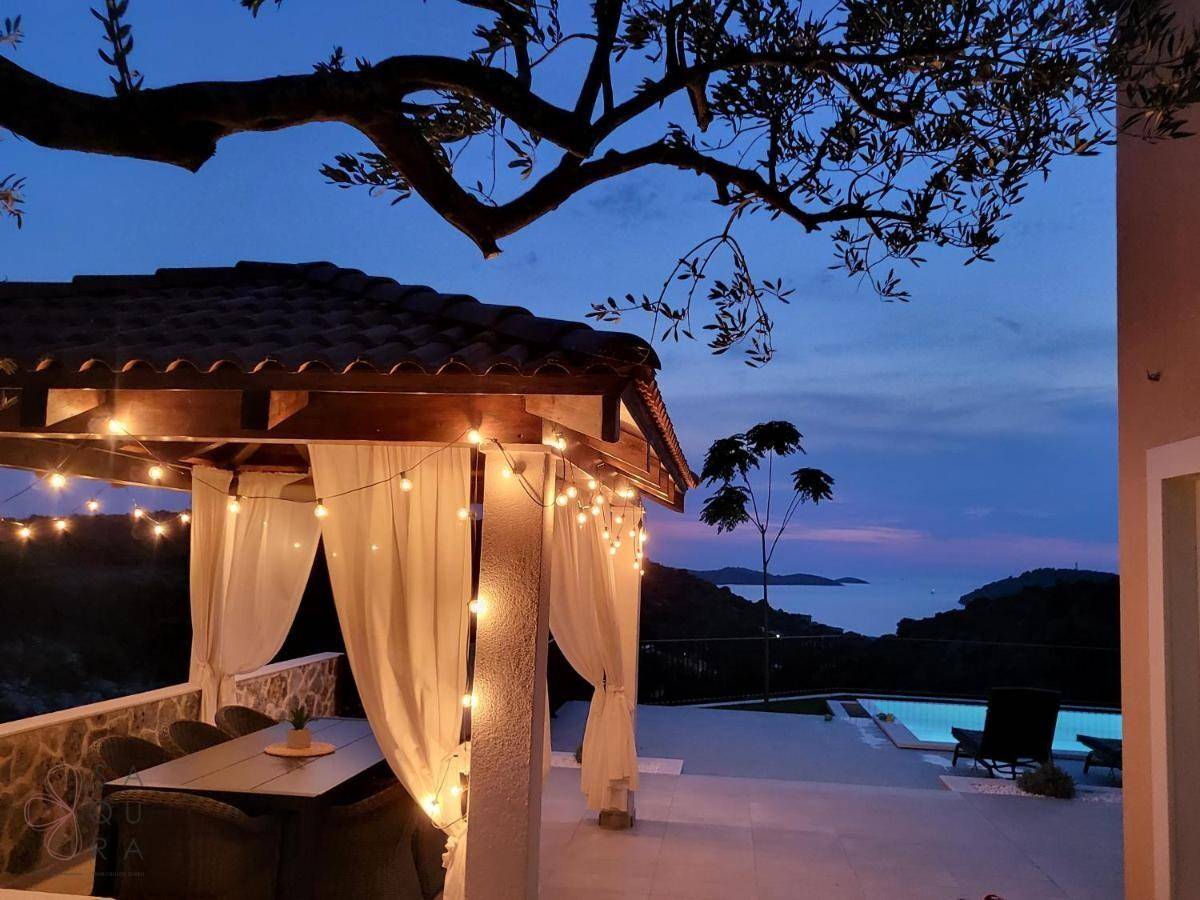 Romantischer Pavillon mit Esstisch und Lichterketten bei Dämmerung, mit Blick auf das Meer.