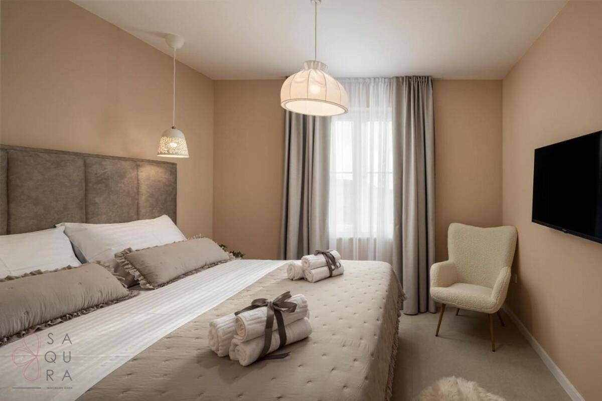 Ruhiges Schlafzimmer mit großem Fenster, bequemen Möbeln und einem Flachbildfernseher an der Wand.
