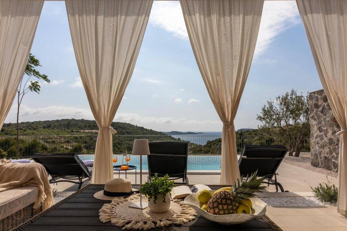 Einladende überdachte Terrasse mit frischen Früchten und einem weiten Blick auf das Meer und die Landschaft.