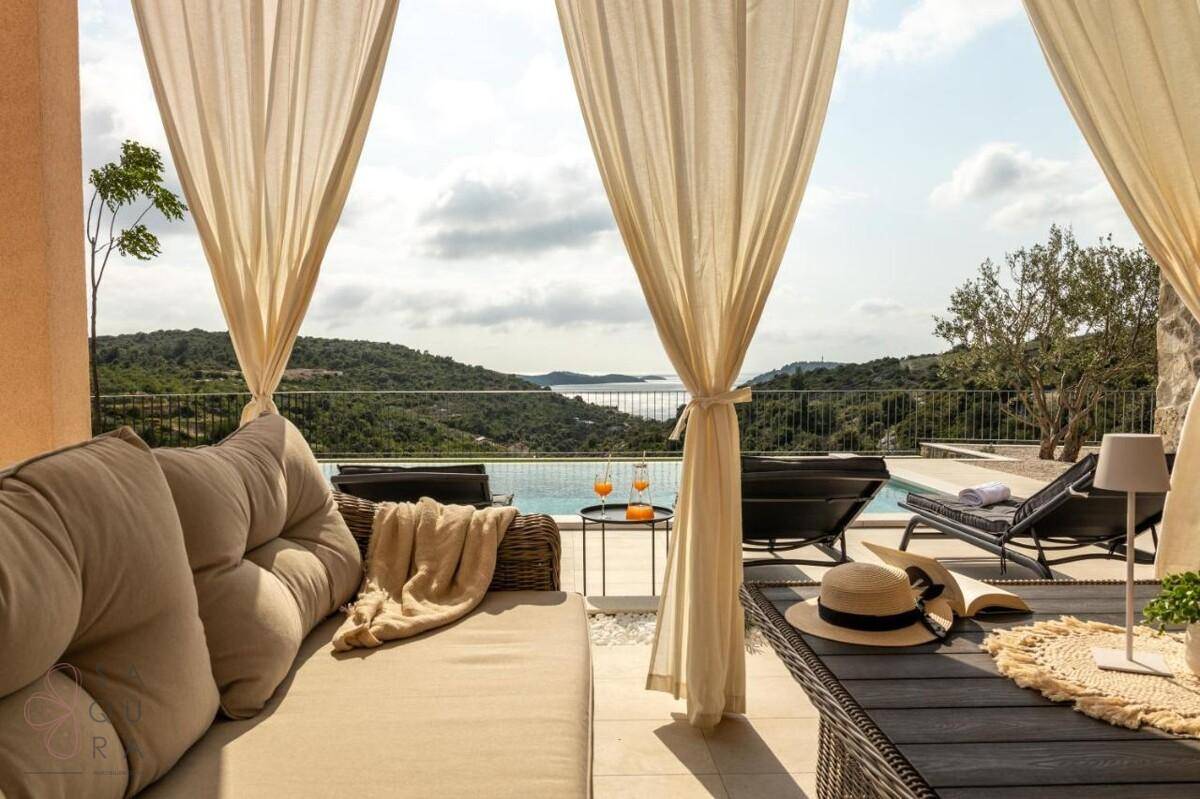 Einladende überdachte Terrasse mit bequemen Lounge-Möbeln und Panoramablick auf das Meer.