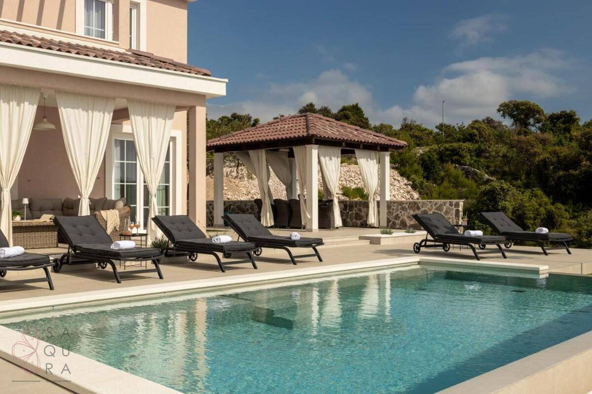 Außenbereich der Villa mit Pool, Liegestühlen und einem charmanten Pavillon, umgeben von Natur.