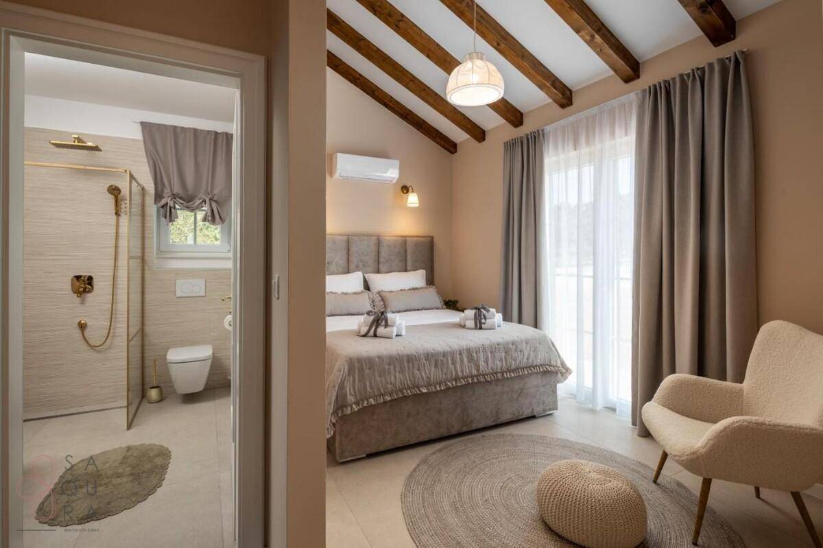 Charmantes Schlafzimmer mit sichtbaren Holzbalken, Klimaanlage und direktem Zugang zum Badezimmer.