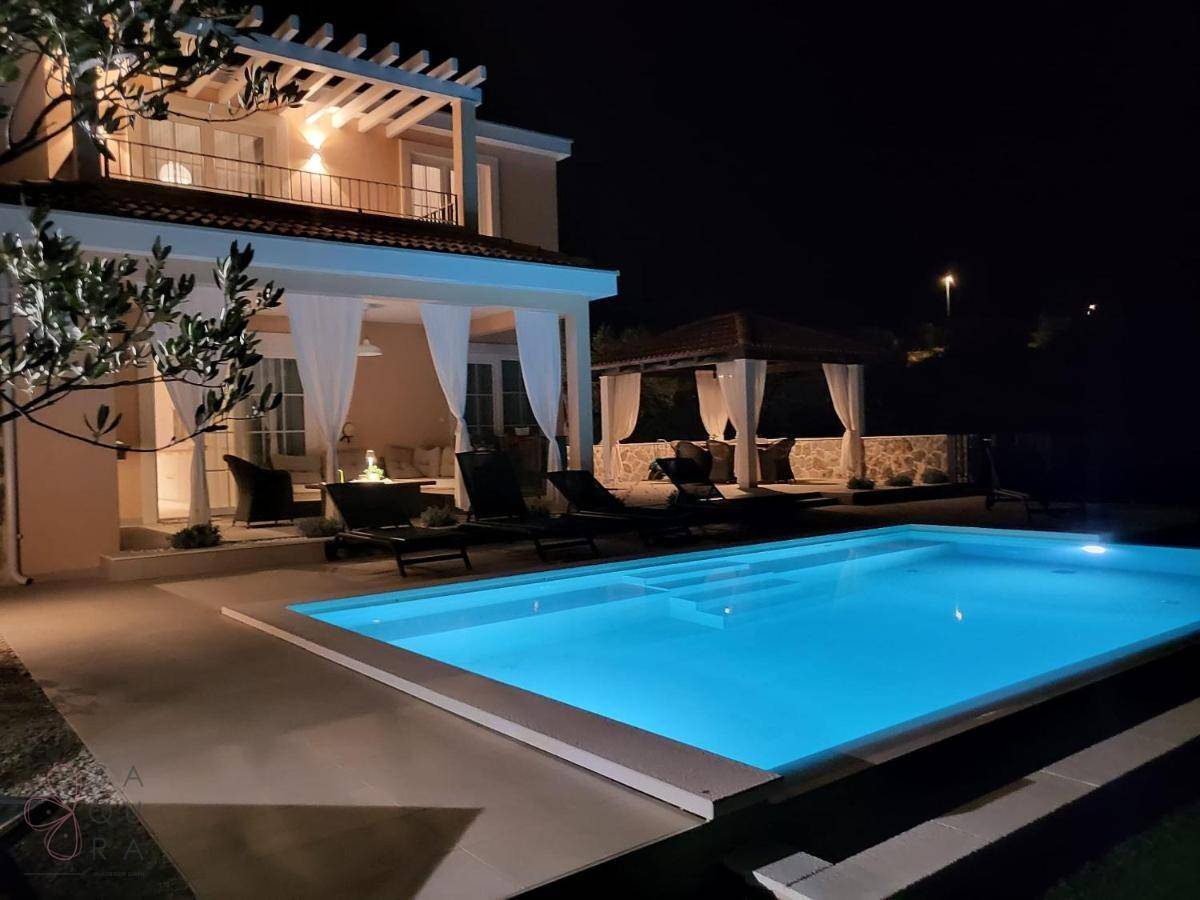 Beleuchtete Villa bei Nacht mit glitzerndem Pool und gemütlichem Pavillon, perfekt für Abendstunden.
