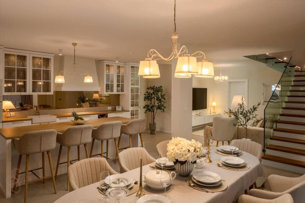 Geräumiger Wohn-Essbereich mit offener Küche und eleganter Treppe, ideal für geselliges Beisammensein.