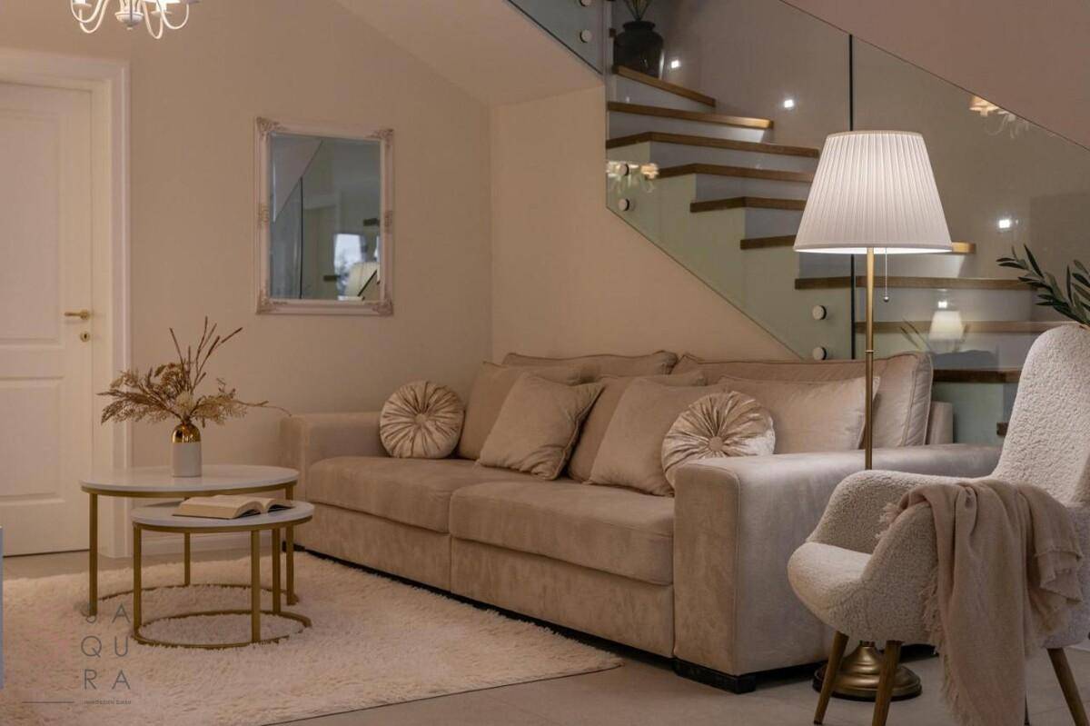 Gemütliches Wohnzimmer mit beigem Sofa, Teppich und einer stilvollen Stehlampe, schafft eine warme Atmosphäre.