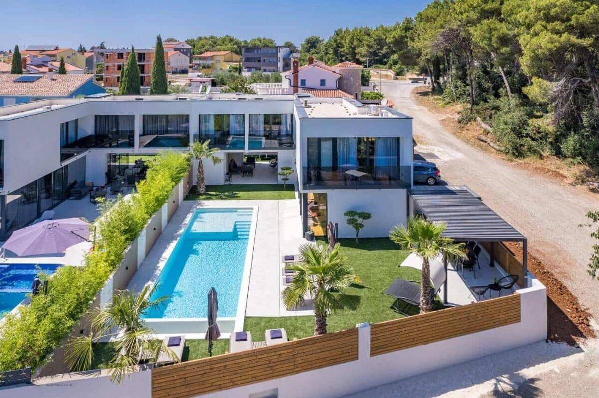 Luftaufnahme der modernen Villa mit Poolbereich und umliegender Wohnsiedlung.