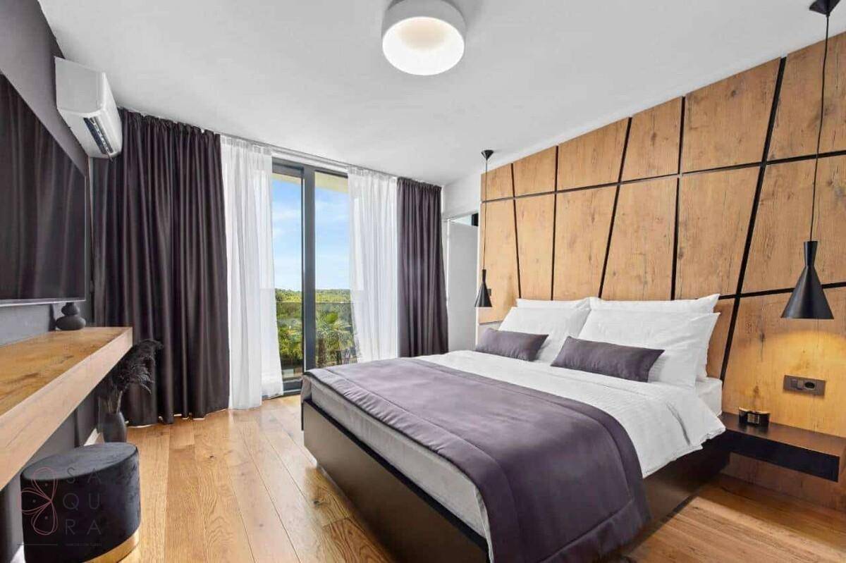 Helles Schlafzimmer mit Holzwandverkleidung, Parkettboden und Zugang zum Balkon.