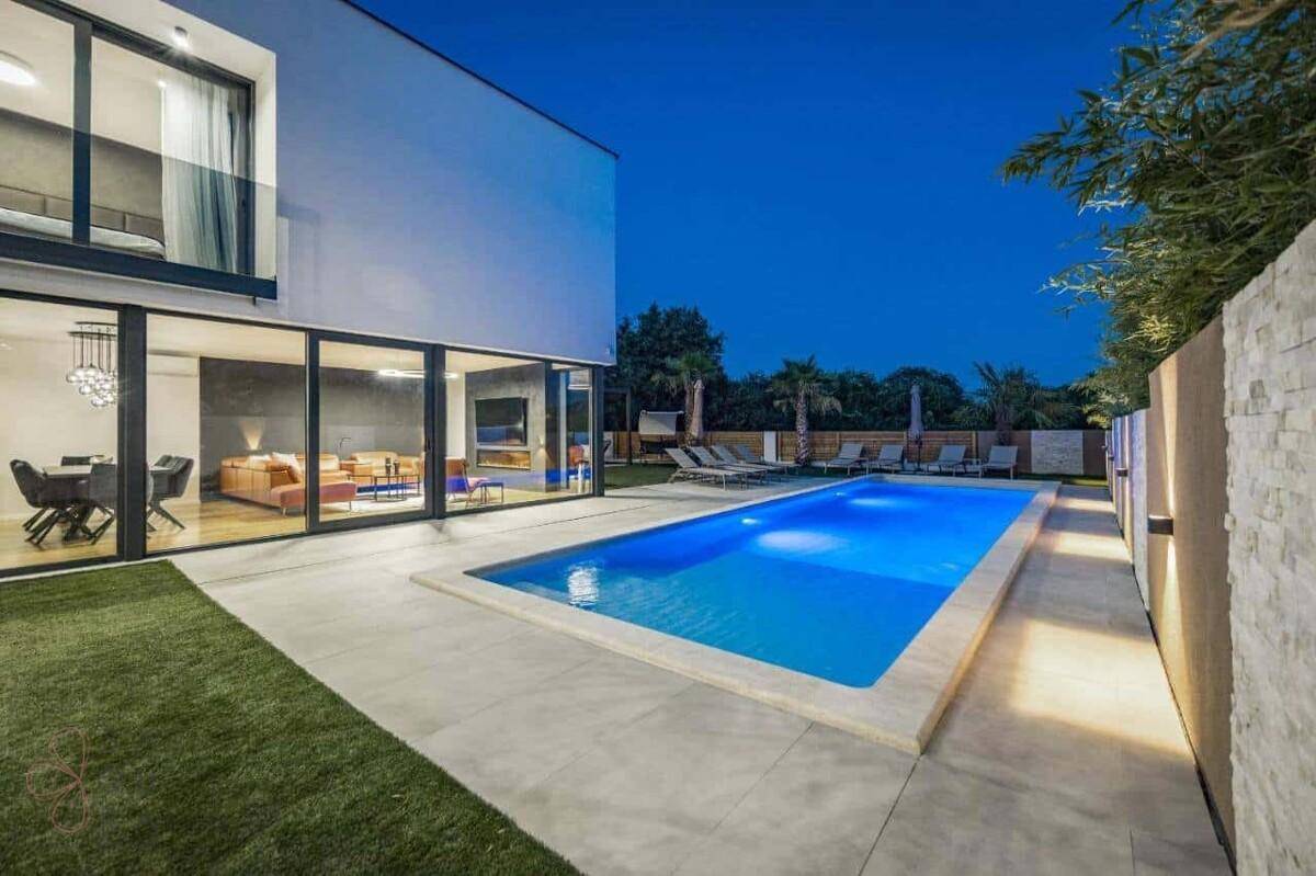 Moderne Villa mit langem Pool, Liegebereich und Blick auf die umliegende Natur.