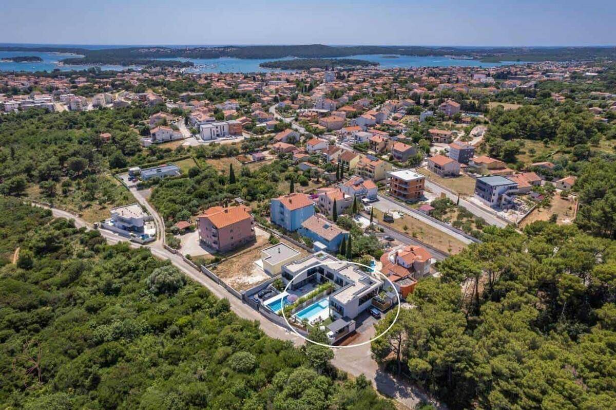 Weitläufige Luftaufnahme der modernen Villa mit Pool in einer grünen Wohngegend.