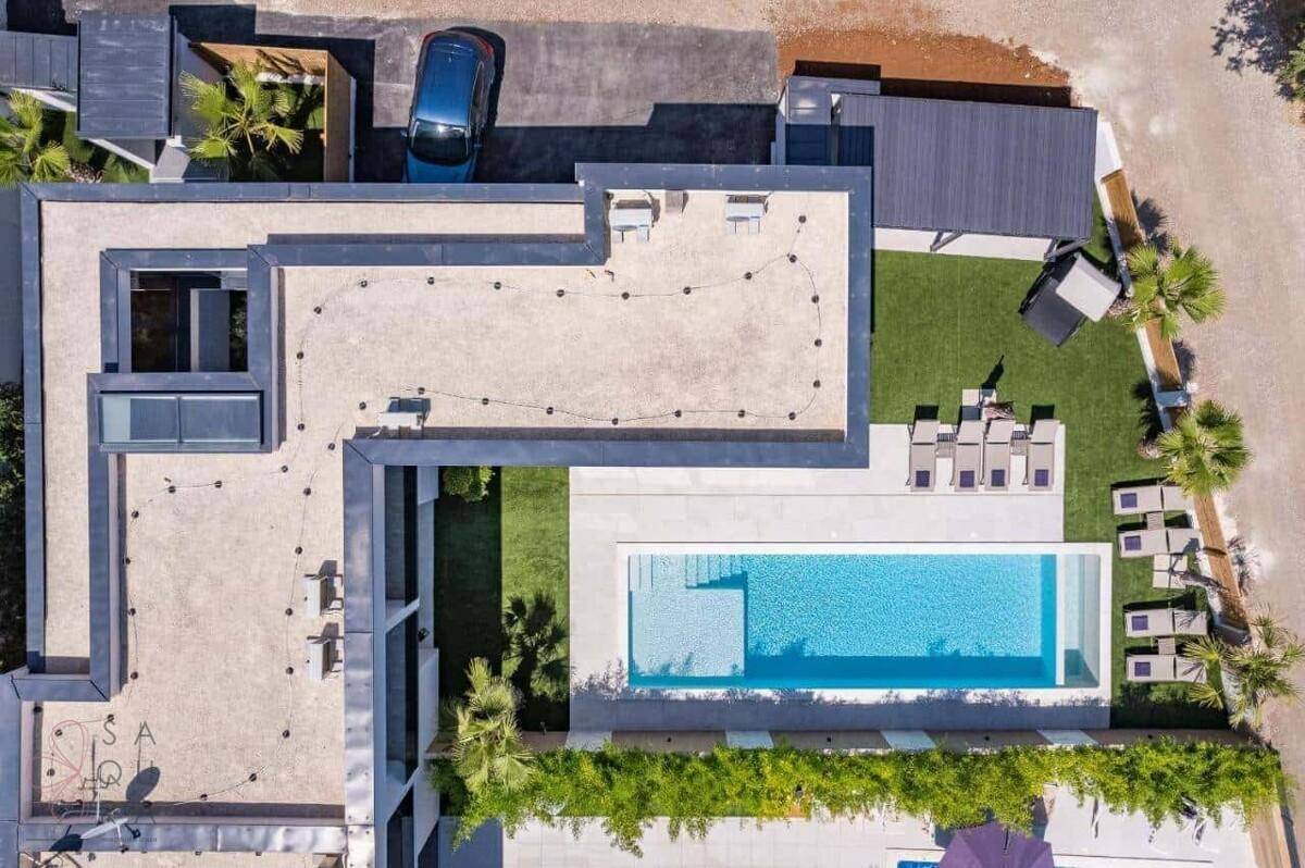 Draufsicht der modernen Villa mit Flachdach, Pool und Gartenbereich.