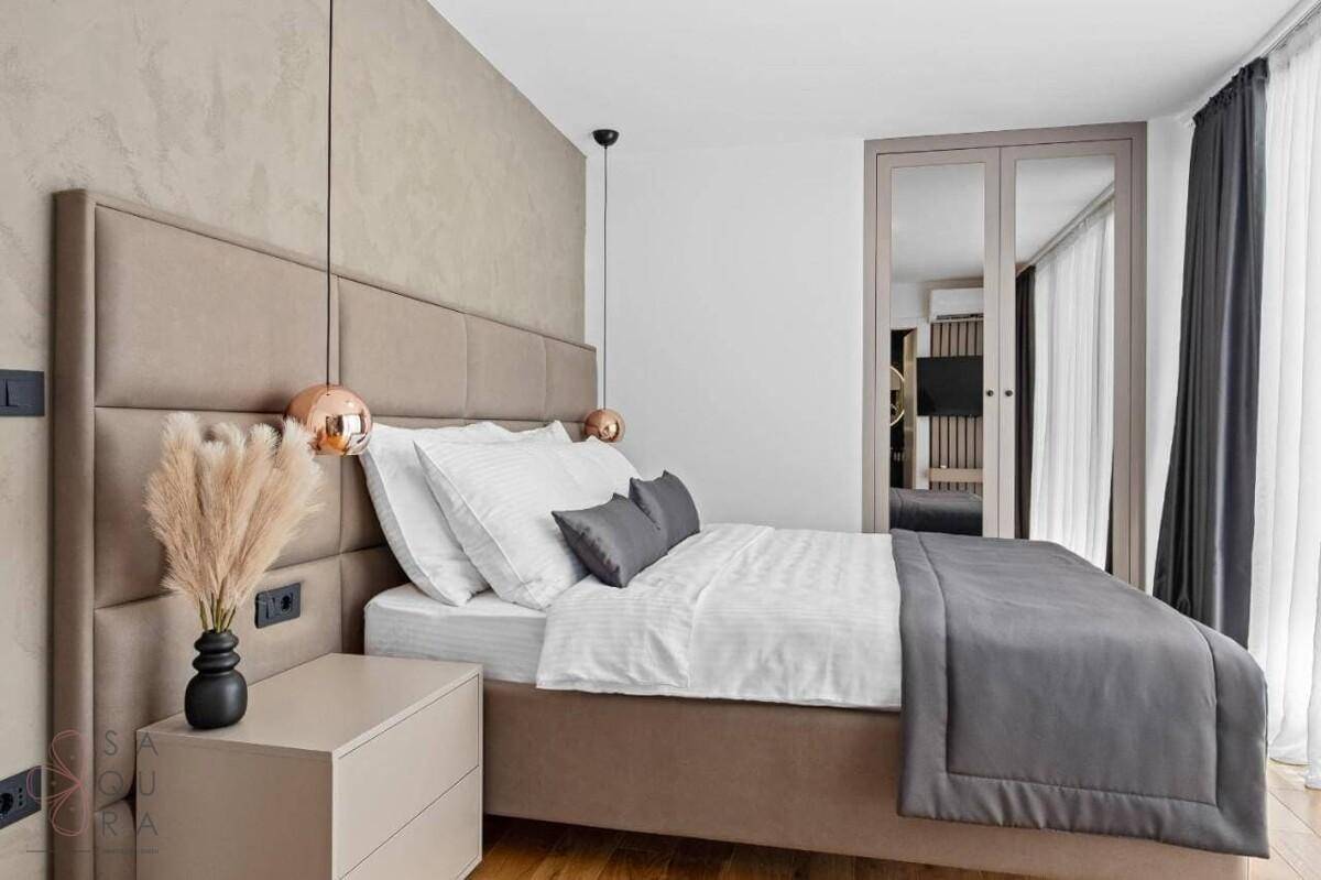 Gemütliches Schlafzimmer mit gepolstertem Kopfteil, Nachttischen und indirekter Beleuchtung.