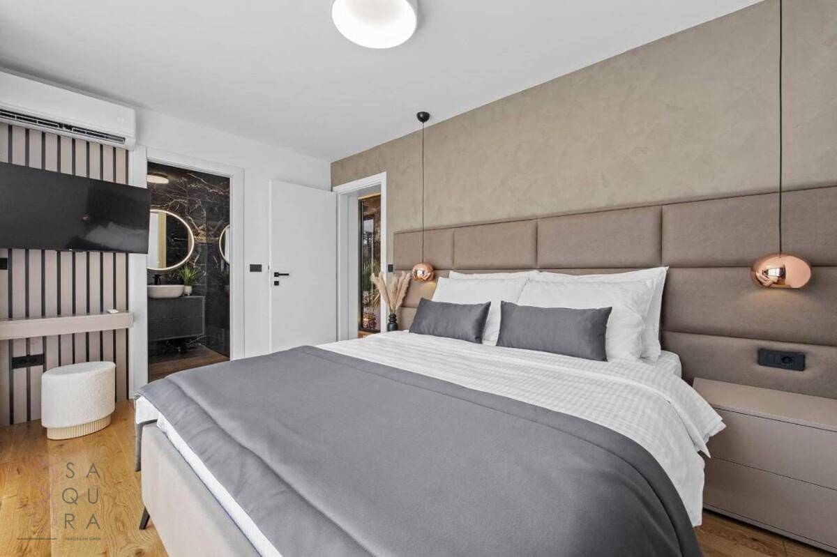 Elegantes Schlafzimmer mit gepolstertem Bett, Klimaanlage und Zugang zum luxuriösen Bad.