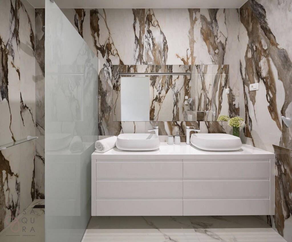 Elegantes Badezimmer mit Marmorwänden, Doppelwaschbecken und begehbarer Dusche.