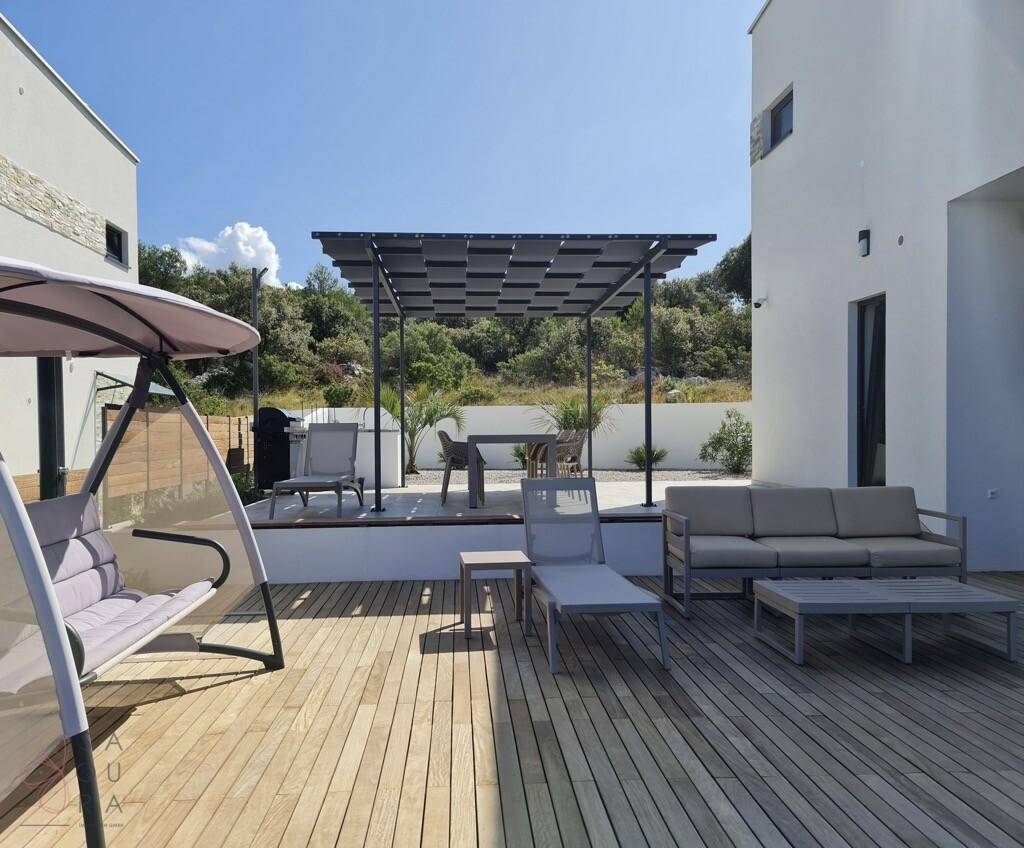 Geräumiges Holzdeck mit Outdoor-Möbeln, Schaukel und Pergola im Freien.
