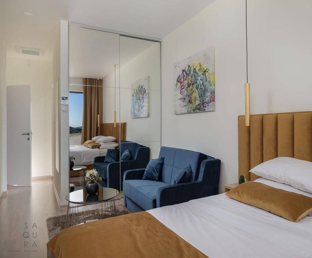 Helles Schlafzimmer mit Doppelbett, Sofa und großem Spiegelschrank.