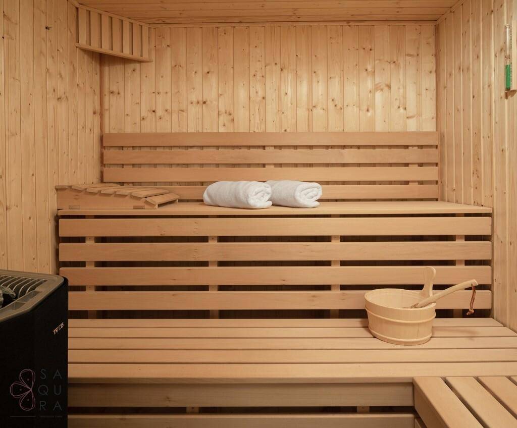 Innenansicht einer modernen Holzsauna mit Bänken und Heizofen.