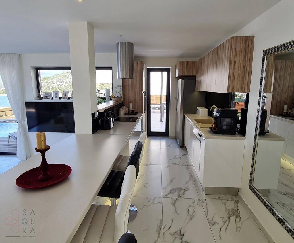 Moderne Küche mit weißen Hochglanzfronten, Holzdetails und Frühstücksbar.