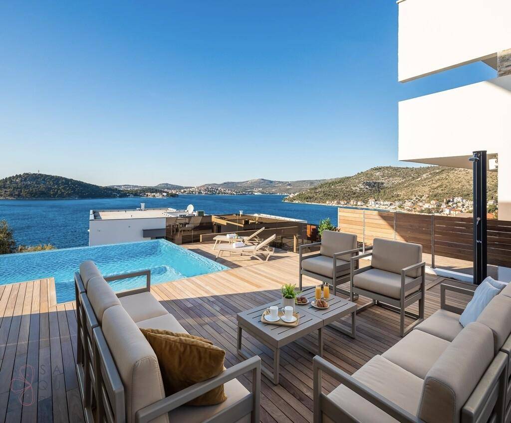 Komfortable Outdoor-Lounge auf dem Holzdeck mit Infinity-Pool und Meerblick.