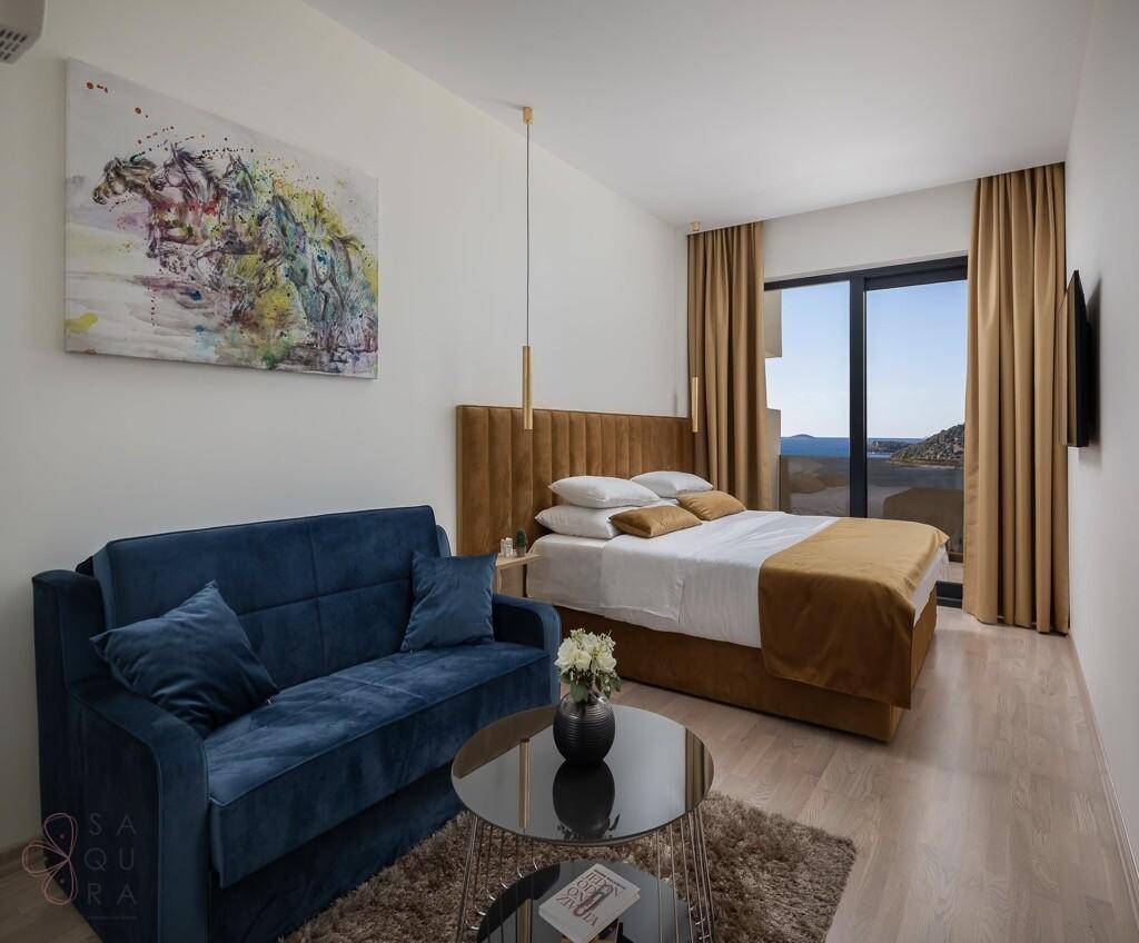 Gemütliches Schlafzimmer mit Doppelbett, Sofa und großem Fenster mit Meerblick.